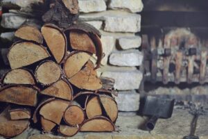 Logs stacked up next to a stone fireplace.